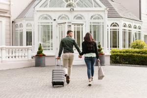 a man and a woman walking with a suitcase at Tullyglass House Hotel in Ballymena