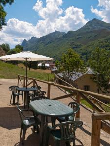 un patio con mesas, sillas y una sombrilla en Hotel Rural Somiedo, en Valle de Lago