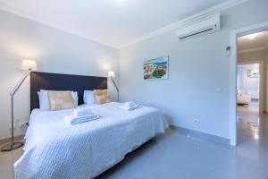 拉戈斯Boa Vista - Golf View Villa的一间白色的卧室，有一张大床，上面放着毛巾