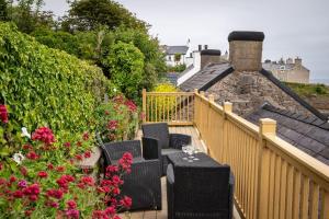 a balcony with chairs and flowers on a house at Glan Y Don Moelfre in Moelfre +22 photos