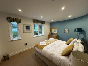 a bedroom with a bed and two windows at Trewhiddle Retreat V10 by Together Travel - Luxury 4-Bedroom Villa in St Austell