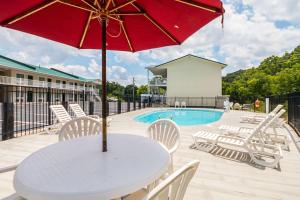 a white table with a red umbrella next to a pool at Quality Inn in Weston