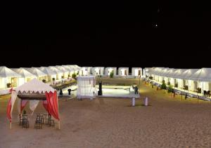 un gruppo di tende sulla spiaggia di notte di Saffron Heritage Desert Camp a Jaisalmer