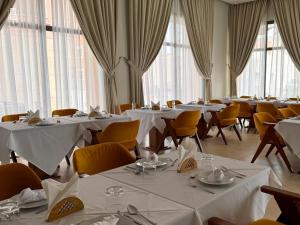 a dining room with white tables and yellow chairs at MH HOTEL LA CASA in Laayoune