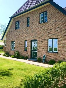 a brick house with a green door and windows at Deichhof-Knudsen in Oldsum