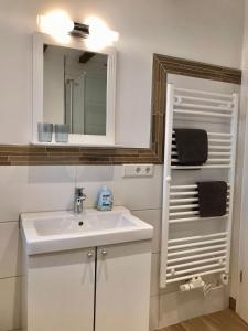 a white bathroom with a sink and a mirror at Deichhof-Knudsen in Oldsum
