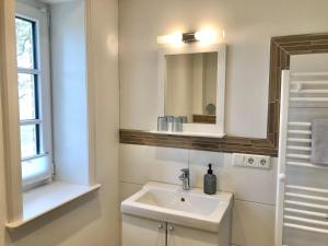a white bathroom with a sink and a mirror at Deichhof-Knudsen in Oldsum +28 photos