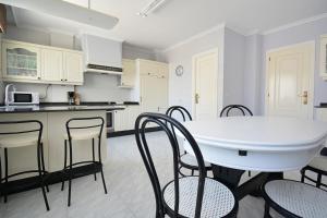 a white kitchen with a white table and chairs at Enorme TRIPLEX en el centro de O Grove in O Grove +34 photos