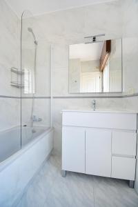 a white bathroom with a sink and a tub and a mirror at Enorme TRIPLEX en el centro de O Grove in O Grove