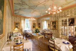 uma sala de jantar com mesas e cadeiras e um lustre em Hotel Restaurant Du Parc em Thann