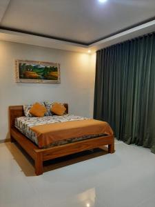 Pondok Giri 3 في جيمباران: غرفة نوم بسرير ونافذة مع ستائر خضراء