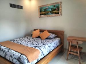 Pondok Giri 3 في جيمباران: غرفة نوم صغيرة مع سرير وطاولة +صورتان