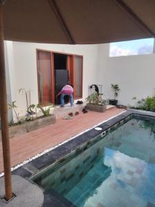 Pondok Giri 3 في جيمباران: شخص واقف بجانب مسبح