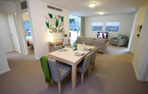 Domain Serviced Apartments في بريزبين: غرفة معيشة مع طاولة وكراسي وأريكة