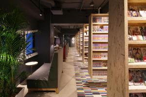 a book store with a long aisle with books at Booth Netcafe & Capsule in Tokyo
