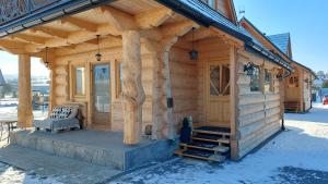 a cabin with a porch and a bench on the porch at Eco Domki Podhalanka in Witów
