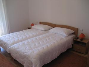 a bedroom with a large white bed with two pillows at Villa Rozic in Cavtat