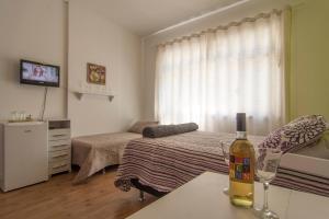 a room with a bed and a bottle of wine on a table at Studio 202 in Petrópolis