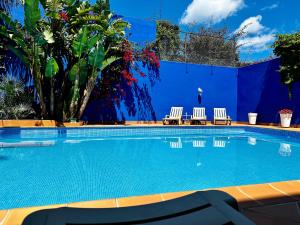 a swimming pool with two chairs and a blue wall at Haddad's for families in Tangier
