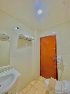 a bathroom with a sink and a wooden door at Pia Hotel in Cirebon