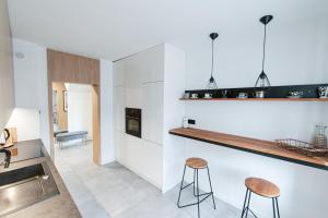 a kitchen with white walls and a counter with stools at Apartament Batorego in Luboń