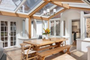a conservatory dining room with a wooden table and benches at Marble Bridge Farm By The Butler Collection in Chichester