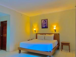 a bedroom with a bed and two lights on the wall at Pia Hotel in Cirebon