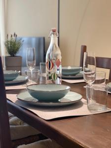 a table with a bottle and plates and wine glasses at Fonderia's Home - Parcheggia Senza Pensieri! in Treviso