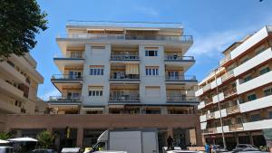 a tall white building with cars parked in front of it at Appartamento Ostia Enjoy in Lido di Ostia