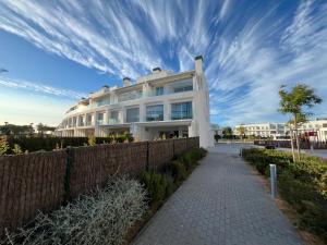 a white building with a fence next to a sidewalk at Beach House Costa Ballena in Chipiona