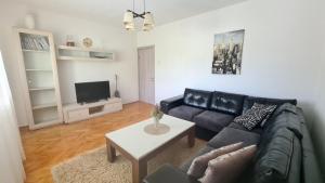 a living room with a black leather couch and a tv at Apartman Stefan in Tivat