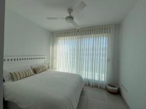 a white bedroom with a bed and a window at Beach House Costa Ballena in Chipiona +28 photos
