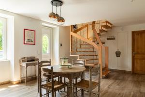 a dining room with a wooden table and a spiral staircase at CoGîte A Condat in Le Grand-Bourg