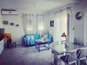 a living room with a blue couch and a table at Tararas apartments in Nea Michaniona
