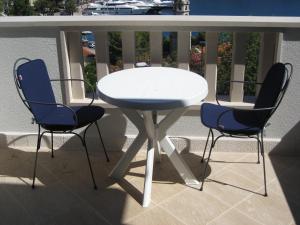 a white table and two blue chairs on a balcony at Villa Rozic in Cavtat