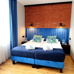 a bedroom with a blue bed with a brick wall at Villa Magna in Gdynia