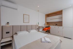 a white bedroom with two beds and a kitchen at Bliss Apartments in Sutomore