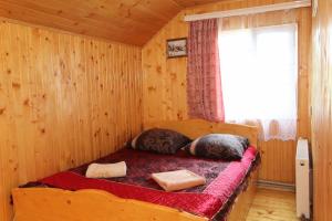 a bed in a wooden room with a window at Гірська Хатина in Mykulychyn