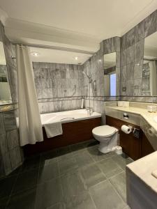 a bathroom with a tub and a toilet and a sink at Cavendish Hotel in Eastbourne