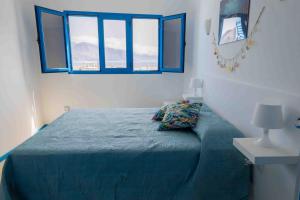 a bedroom with a bed with blue sheets and windows at La Avenida Las Nieves Agaete in Puerto de las Nieves