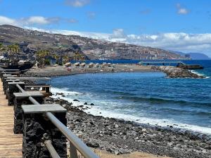 a beach with benches and people on the beach at Vivienda Carolina in Santa Cruz de Tenerife