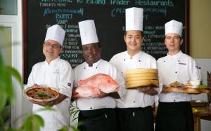 a group of chefs standing in a kitchen holding a turkey at Coral Strand Smart Choice in Beau Vallon