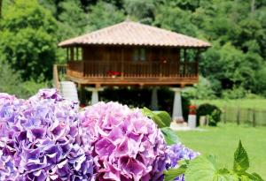 a gazebo in a park with purple flowers at Casa con Jardín y Barbacoa en Llanes – Molinin in Villanueva de Ardisana