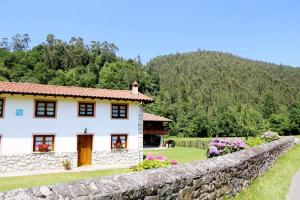 a white house with a stone wall at Casa Vacacional el Molinin in Villanueva de Ardisana