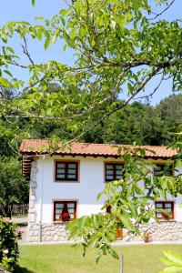 a white house with a red roof at Casa Vacacional el Molinin in Villanueva de Ardisana