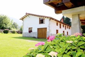 a white house with flowers in front of it at Casa con Jardín y Barbacoa en Llanes – Molinin in Villanueva de Ardisana