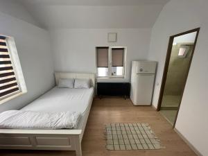 a small bedroom with a bed and a refrigerator at Compact House in Cluj-Napoca