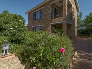 a brick house with a statue in front of a garden at Ascot Gardens Self Catering in Cape Town