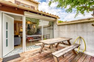 ein hölzerner Picknicktisch auf einer Terrasse mit einer Glasschiebetür in der Unterkunft Maison avec terrasse climatisation in Saintes-Maries-de-la-Mer