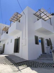 a white building with black doors and stairs on it at Galani Mirtia Guest House in Skiros